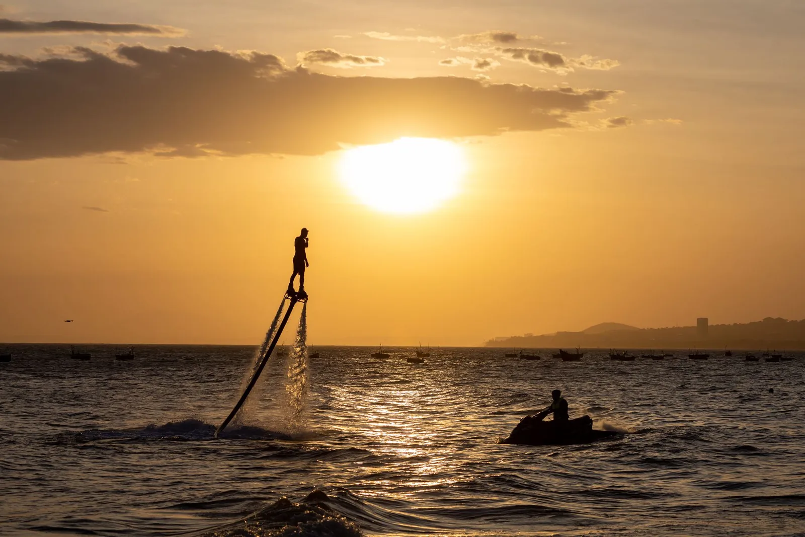 En flyboardåkare ovanför havet med en vattenskoter intill