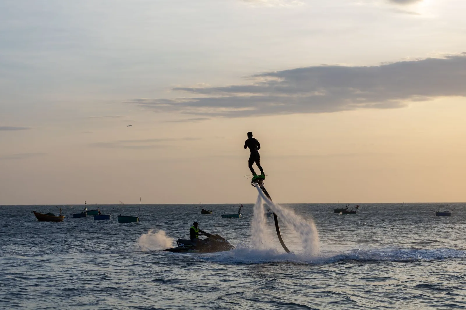 Flyboardåkare med vattenstrålar och slang ovanför havet